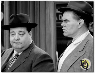 Tegenover Jackie Gleason (L) misschien wel George Mathews (R) én van zijn meest memorabele rollen was die van Harvey in "The Bensonhurst Bomber" een aflevering van de TV-reeks&nbsp;"The Honeymooners". (1956).  Klik op de foto om de clip uit de reeks te zien...
