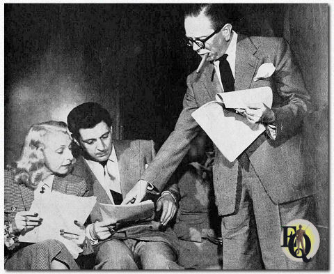 Goodman Ace, schrijver-producer regisseur en co-ster van CBS' "mr.ace & JANE", wijst een lachlijn aan voor zijn vrouw Jane en omroeper Ken Roberts tijdens de repetitie van de heldere nieuwe zaterdag comedy serie. Roberts komt in het script ook voor als de opgewekte radio-omroeper die naast de Aces woont. (Maa 1948).